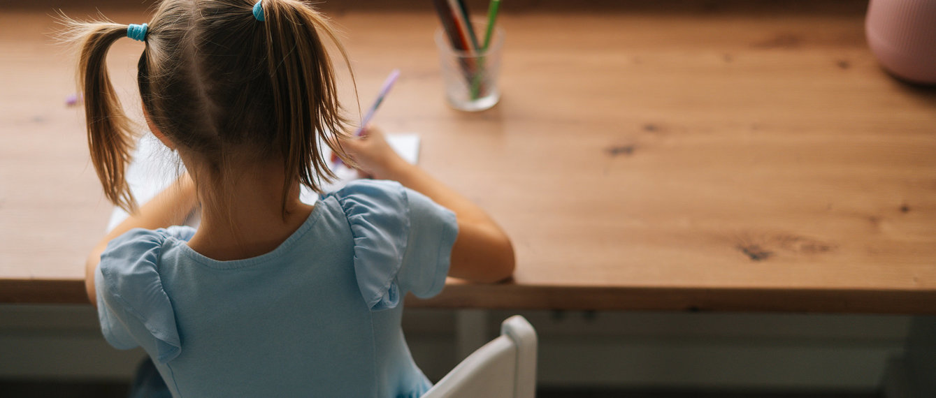 Mädchen sitzt am Schreibtisch und macht Hausübung